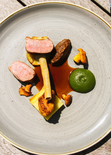 A plate of food and glass of water on a wooden table.
