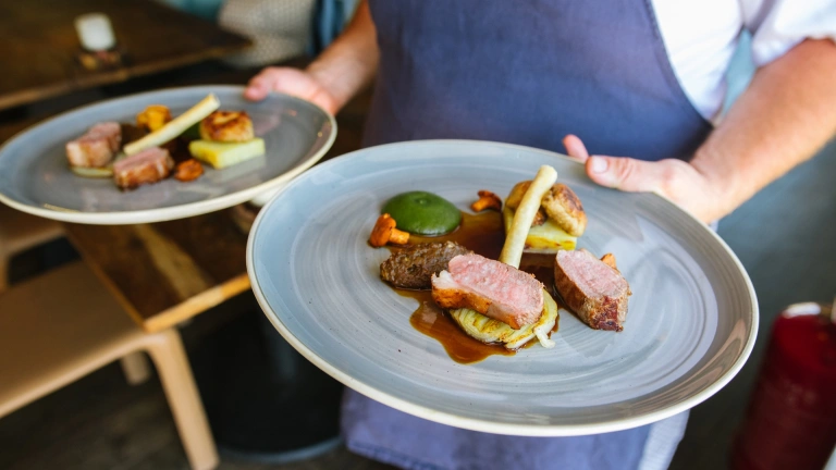 Ein Koch, der zwei Teller mit Essen trägt.
