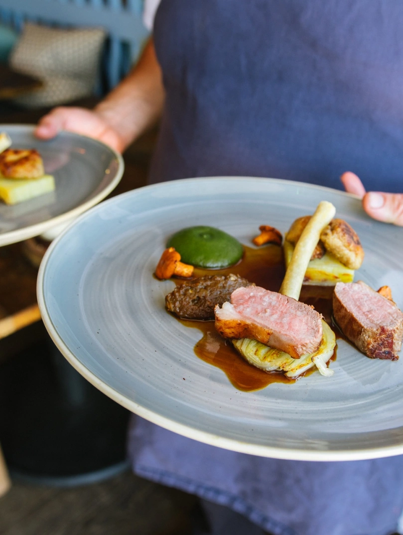 Ein Koch, der zwei Teller mit Essen trägt.